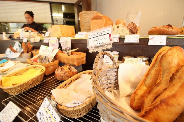 ラ・マン・キ・パンス(フランス語で考える手を意味する店名です。一番人気のフランス小麦100％のバゲットや北海道小麦の食パン等、50種類以上のパンは次々に売れていきます。)